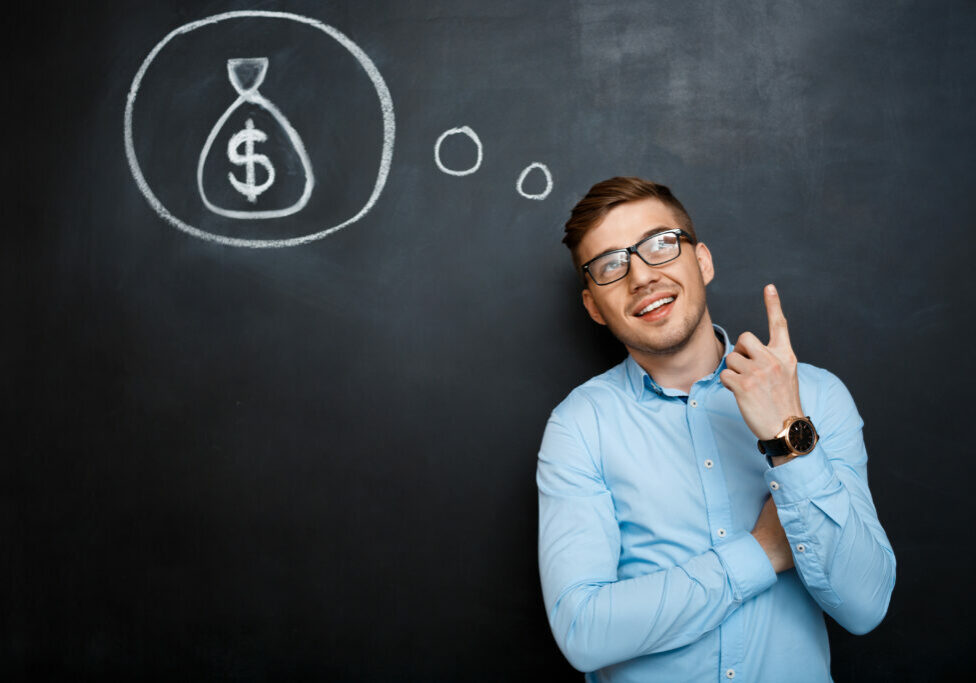 Portrait of minded, suited man standing crossed hands over blackboard. money concept